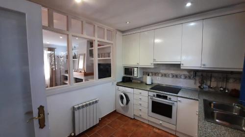 a kitchen with white cabinets and a dishwasher at Aurea in La Losa