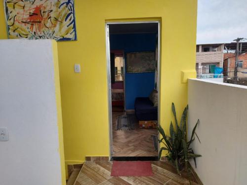 a room with a yellow wall and a mirror at Casa inteira com AR 2/4 in Salvador