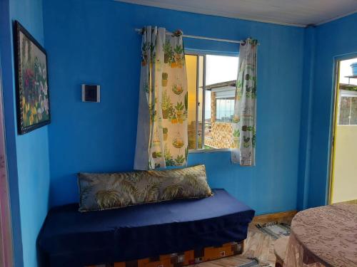 a blue room with a pillow and a window at Casa inteira com AR 2/4 in Salvador