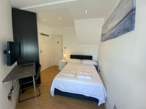 a bedroom with a bed and a desk and a television at 1 HENDON OLD one in Golders Green