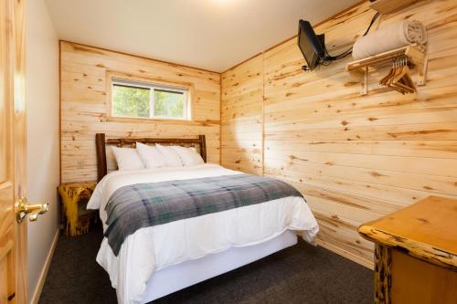 a bedroom with a bed in a wooden wall at Beargrass Lodging & RV Resort in Hungry Horse