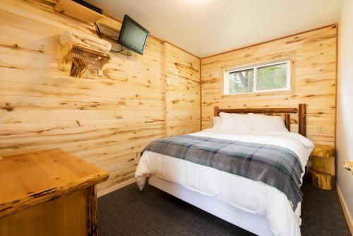 a bedroom with a bed in a wooden wall at Beargrass Lodging & RV Resort in Hungry Horse