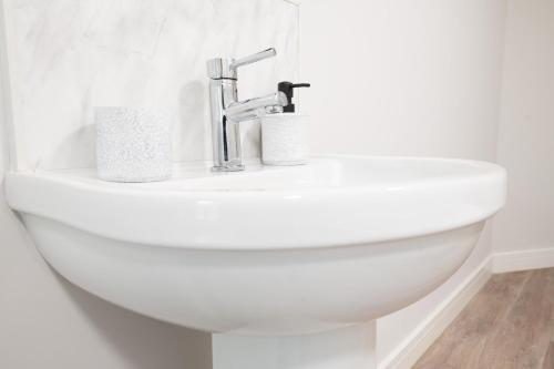 a white toilet with two rolls of toilet paper on it at 3 bedroom Cannock flat ideal for groups in Great Wyrley