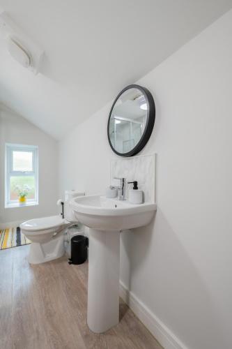 a white bathroom with a sink and a mirror at 3 bedroom Cannock flat ideal for groups in Great Wyrley