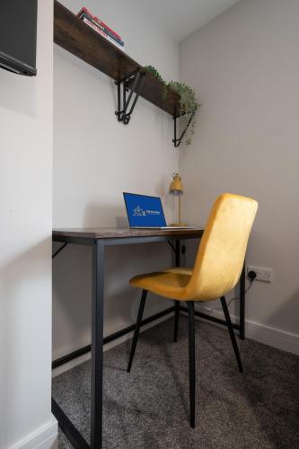 a desk with a laptop and a yellow chair at 3 bedroom Cannock flat ideal for groups in Great Wyrley
