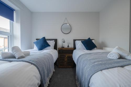 sypialnia z 2 łóżkami i niebieskimi poduszkami w obiekcie 3 bedroom Cannock flat ideal for groups w mieście Great Wyrley