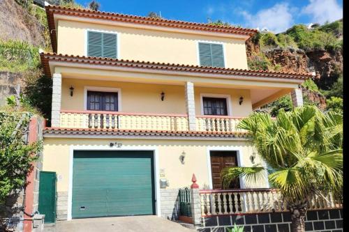 a house with a green garage door in front of it at Gomes house in Ponta do Sol