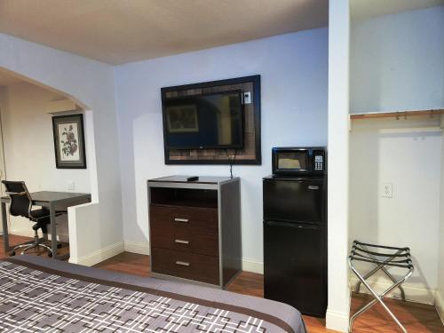a room with a bed and a desk and a television at Express Inn Tomball in Tomball