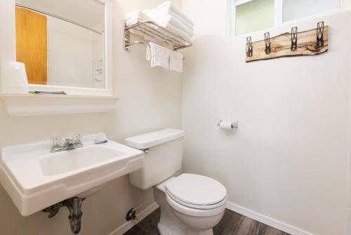 a white bathroom with a sink and a toilet at Beargrass Lodging & RV Resort in Hungry Horse