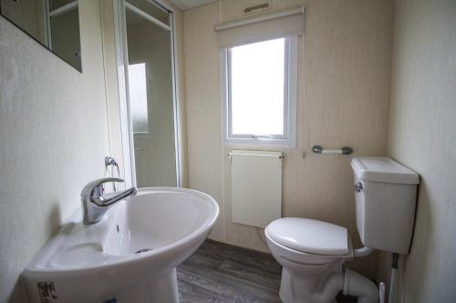 a bathroom with a sink and a toilet and a window at Lovely 8 Berth Caravan At Southview Holiday Park In Skegness Ref 33061c in Skegness