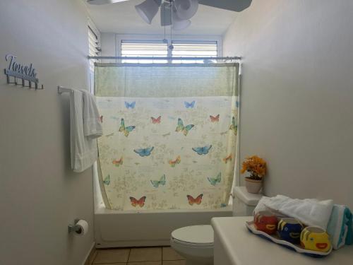 e bagno con servizi igienici e tenda doccia con farfalle. di Relaxing Hillside Village Apartment a Rio Grande