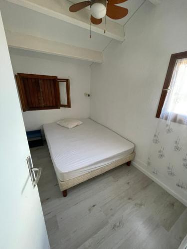 um pequeno quarto com uma cama e uma ventoinha de tecto em Appartement bord de mer em Sainte-Marie-la-Mer