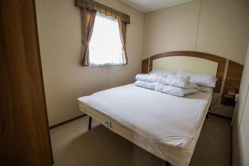 um quarto com uma cama com lençóis brancos e almofadas em 8 Berth Caravan With Decking At Sunnydale In Lincolnshire Ref 35087s em Louth