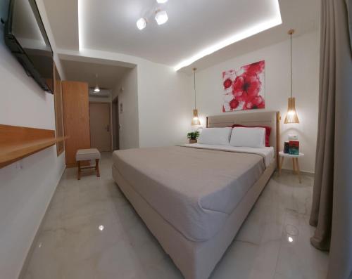 a white bedroom with a large bed and a television at Wide Blue Luxury Boutique Suites in Neos Marmaras