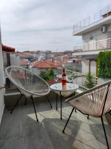 a patio with two chairs and a table with a bottle of wine at Wide Blue Luxury Boutique Suites in Neos Marmaras