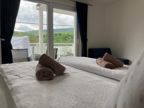 twee bedden in een kamer met een groot raam bij Villa Pliva Lake Jajce in Jajce