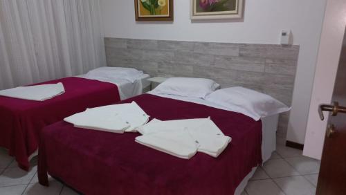 2 Betten mit weißen Handtüchern auf einem Zimmer in der Unterkunft Apto. 2 quartos em Bombinhas (60 m da praia) in Bombinhas