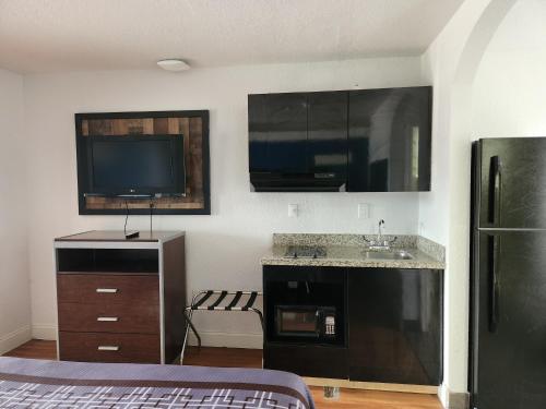 a room with a kitchen with a sink and a tv at Express Inn Tomball in Tomball
