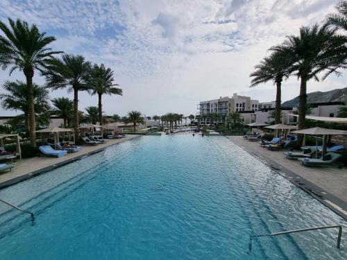 uma grande piscina com palmeiras e edifícios em Shaqa at Address Beach Residence - Fuj em Fujairah