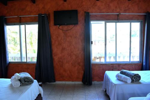 a room with two beds and a tv and windows at Casa Vieja Hotel y Restaurante in San Lorenzo
