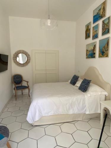 ein weißes Schlafzimmer mit einem Bett und einem Spiegel in der Unterkunft CASA ELISA in Capri