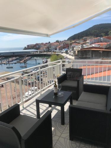 a balcony with a table and chairs and a view of a harbor at Apartamento vista al Puerto de Finisterre in Fisterra