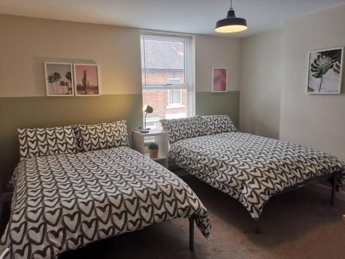 een slaapkamer met 2 bedden en een raam bij NEW Derby Pride Park Arena Moorways 4 bedrooms 7 beds -Spacious contractors or group -FREE PARKING in Derby