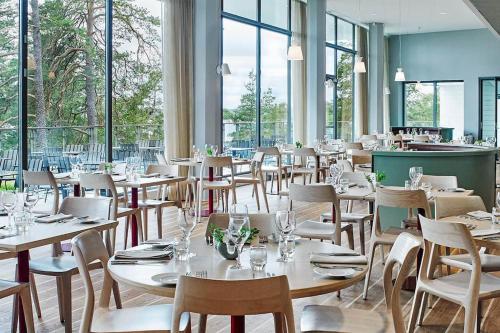 un comedor con mesas, sillas y ventanas en Modern, mysig & exklusiv villa i Skärgården #1, en Estocolmo