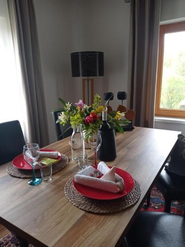 a wooden table with red plates and flowers on it at Ferienhaus Familie Zimmermann in Keutschach am See
