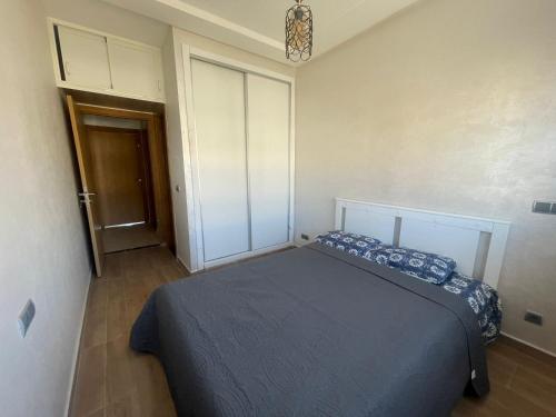 een slaapkamer met een bed met blauwe kussens erop bij Bel Appartement Vue sur Piscine et Mer in Mansouria