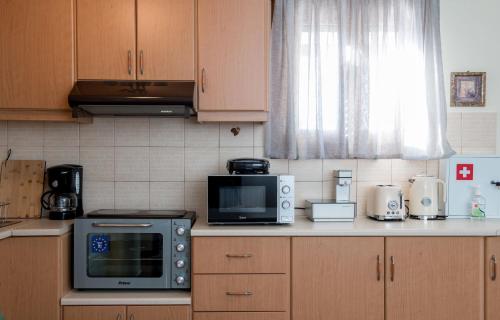 a kitchen with wooden cabinets and a microwave oven at kouremenos beach house East in Angathiás