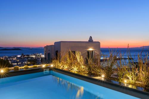 una piscina con vistas al océano por la noche en She Mykonos Boutique Hotel, en Mykonos ciudad