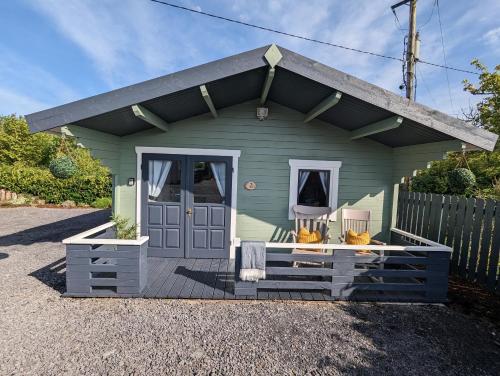 Westport Country Chalets في ويستبورت: منزل صغير أخضر مع باب أزرق