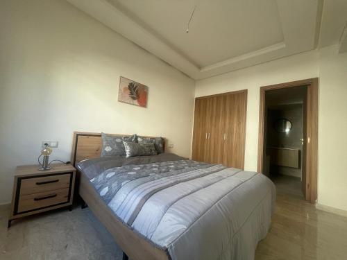 um quarto com uma cama grande e uma mesa de cabeceira em Taj appartement/ aeroport M 5 em Nouaceur