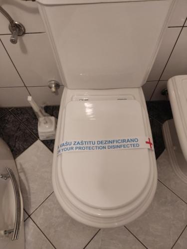 a toilet with a sticker on the seat in a bathroom at Villa Kuna in Sarajevo