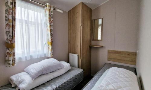 ein kleines Schlafzimmer mit 2 Betten und einem Fenster in der Unterkunft Modern 6 Berth Caravan With Wifi At Martello Beach In Essex Ref 28008pm in Clacton-on-Sea