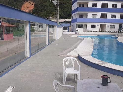 a white chair sitting on a patio next to a swimming pool at Cobertura de Frente Para o Mar e Piscina Village das Ondas in Piúma
