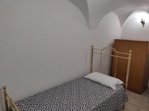 Bett in einem Zimmer mit einer weißen Wand in der Unterkunft Casa Il Carruggio in San Bartolomeo al Mare