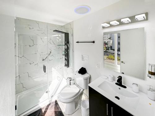 a white bathroom with a toilet and a sink at Vacay Spot experience Luna Sky! 65" TV BAR, BBQ, SHOWER massage jets, music, go to FL Keys in Homestead