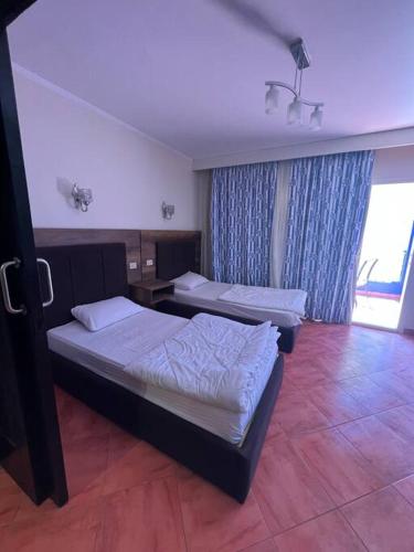- une chambre avec 2 lits et une grande fenêtre dans l'établissement شاليه ببورتو مارينا على البحر٢ غرفه, à El Alamein