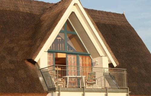 a house with a thatched roof with a balcony at Cozy Apartment In Börgerende-Rethwisch in Börgerende-Rethwisch