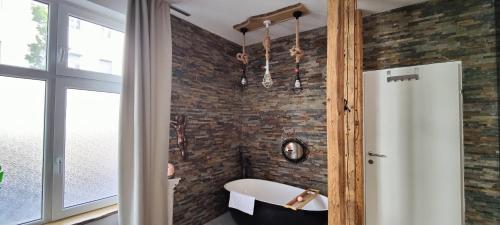 een badkamer met een bakstenen muur en een bad bij XuBa ApartmentRooms Messe Wien Prater in Wenen