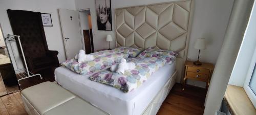 a bedroom with a white bed with a large headboard at XuBa ApartmentRooms Messe Wien Prater in Vienna
