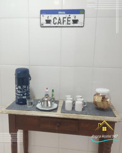 a table with a coffee pot and cups on it at Angra Hostel 147 in Angra dos Reis