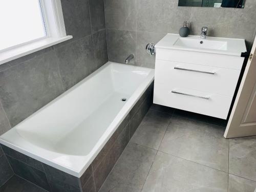 a bathroom with a white bath tub next to a sink at Central Hut Villa in Lower Hutt
