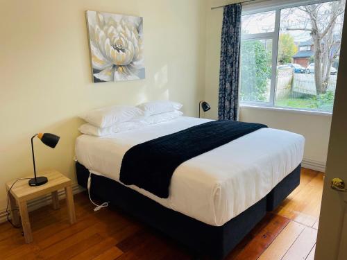 1 dormitorio con 1 cama grande y ventana en Central Hut Villa, en Lower Hutt