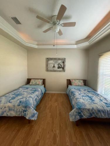 two beds in a room with a ceiling fan at Pool Home in Englewood