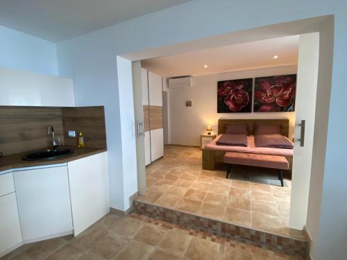 a bedroom with a bed and a kitchen at Nice Place in Stanići