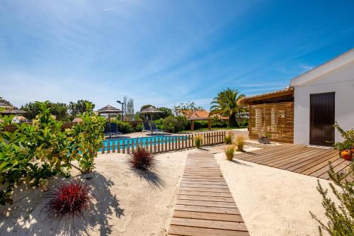 a backyard with a wooden walkway and a swimming pool at Flow Rooms in Comporta