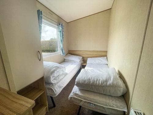 um pequeno quarto com 2 camas e uma janela em Caravan With Decking At Southview Holiday Park In Skegness Ref 33005s em Skegness